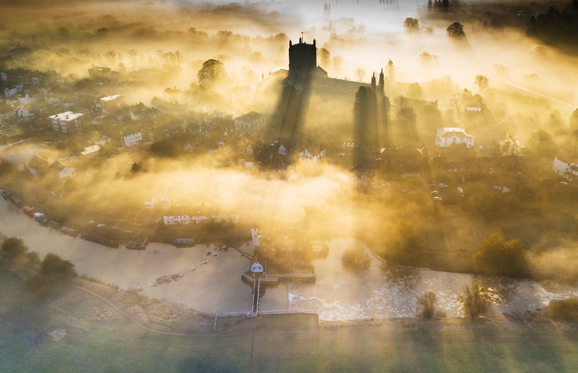 Recognised as one of the UK's finest examples of medieval architecture, the soaring Norman towers of Tewkesbury Abbey have been a recognizable part of Tewkesbury's skyline for almost nine centuries. In this captivating image by Gary Cox, the surrounding mists and golden light only add to the building's ethereal quality.