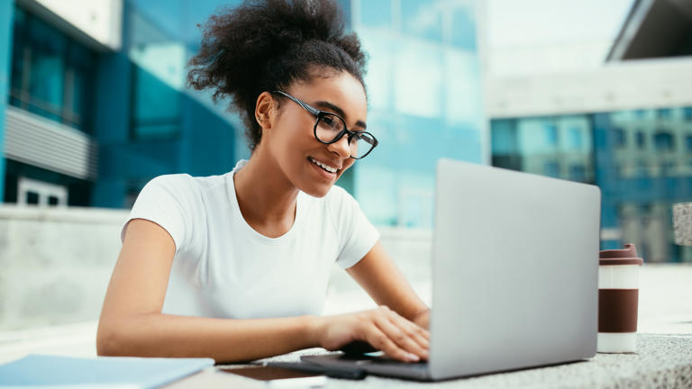 A young, happy woman works on her computer. _iStock-1342036694