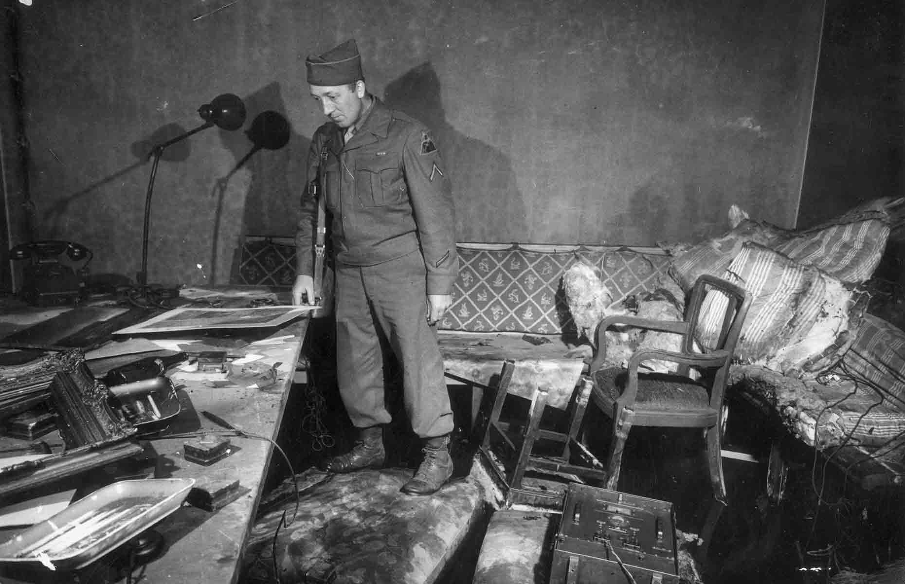 <p>Shortly after they were declared dead, the Red Army began shelling the area around the Reich Chancellery. This photo shows Private First Class Richard Blust of Michigan examining the bunker following their deaths. A fire had destroyed much of the room's contents, but you can still make out an ornate gilded sofa.</p>