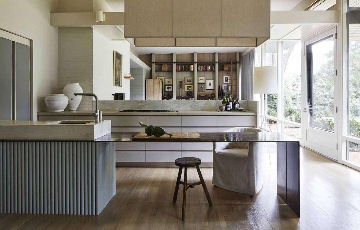 <p>In <a href="https://www.veranda.com/decorating-ideas/a36082855/ken-pursley-charlotte-house-tour/">this mid-century modern kitchen renovated by architect Ken Pursley</a>, sleek cabinets lack hardware in true handleless fashion. A thin, plated-steel prep counter extends off the sink to face the den.</p>