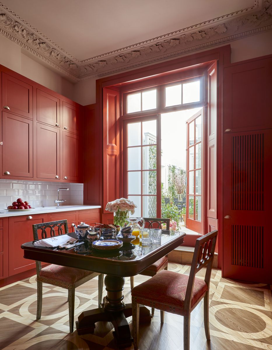 <p>Ravishing red cabinetry packs a powerful punch in the kitchen of this <a href="https://www.veranda.com/decorating-ideas/house-tours/a40726049/philip-vergeylen-london-apartment-home-tour/">glamorous London apartment by Philip Vergeylen</a>. Decorative artist Henry van der Vijver refreshed the original kitchen floors by sanding and staining them in a series of circles and squares that elevate the dramatic cabinets. </p>