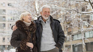 Smiling senior couple walking outdoors on a snowy winter day