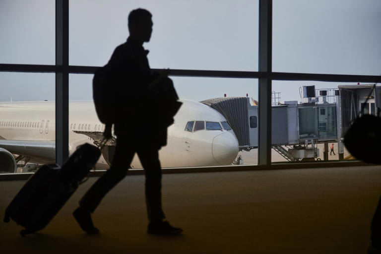 Man walking through an airport with his suitcase