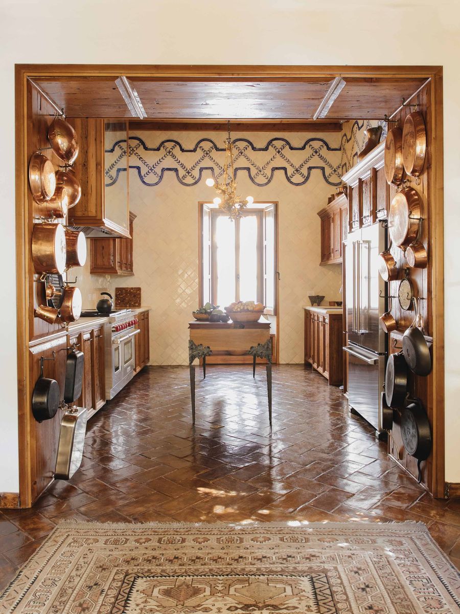 <p>In the small kitchen of <a href="https://www.veranda.com/decorating-ideas/house-tours/a37815045/weisman-fisher-san-miguel-mexico-house-tour/">his San Miguel de Allende, Mexico, home</a>, designer Jeffry Fisher emblazoned the floor-to-ceiling tilework with a hand-painted border. The flooring is hand-burnished, local terra-cotta.</p>