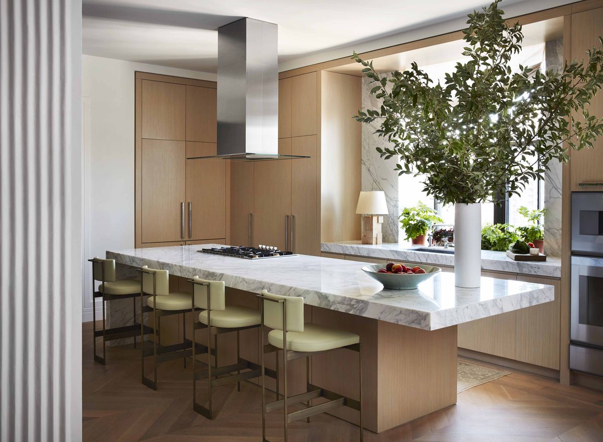 <p>Despite its petite size, <a href="https://www.veranda.com/decorating-ideas/house-tours/a37189762/passal-nyc-apartment-house-tour/">this New York City kitchen designed by Robert Passal</a> accommodates a large island, which not only allows for seating for four but also includes a cooktop. When combined with the wall ovens (at right of frame), the built-in cooktop makes a large-scale range unnecessary and frees up under-counter storage space. Sculptural metal counter stools are finished in antique brass and upholstered in pistachio leather (<a href="https://www.jerrypair.com/">Jerry Pair</a>).</p>
