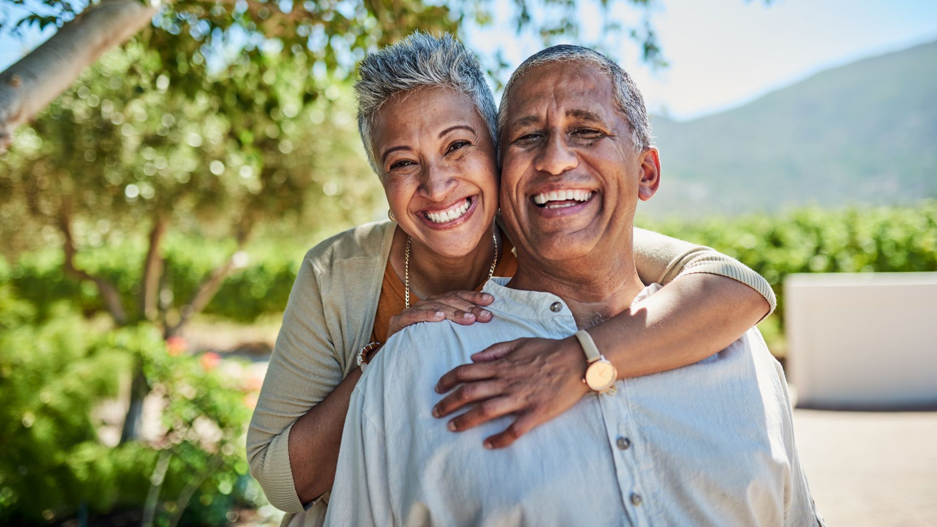 Senior couple, smile and outdoor in nature park showing love, care and happy on a retirement holiday on summer day. Portrait of elderly man and woman together for fresh air and tree view on vacation