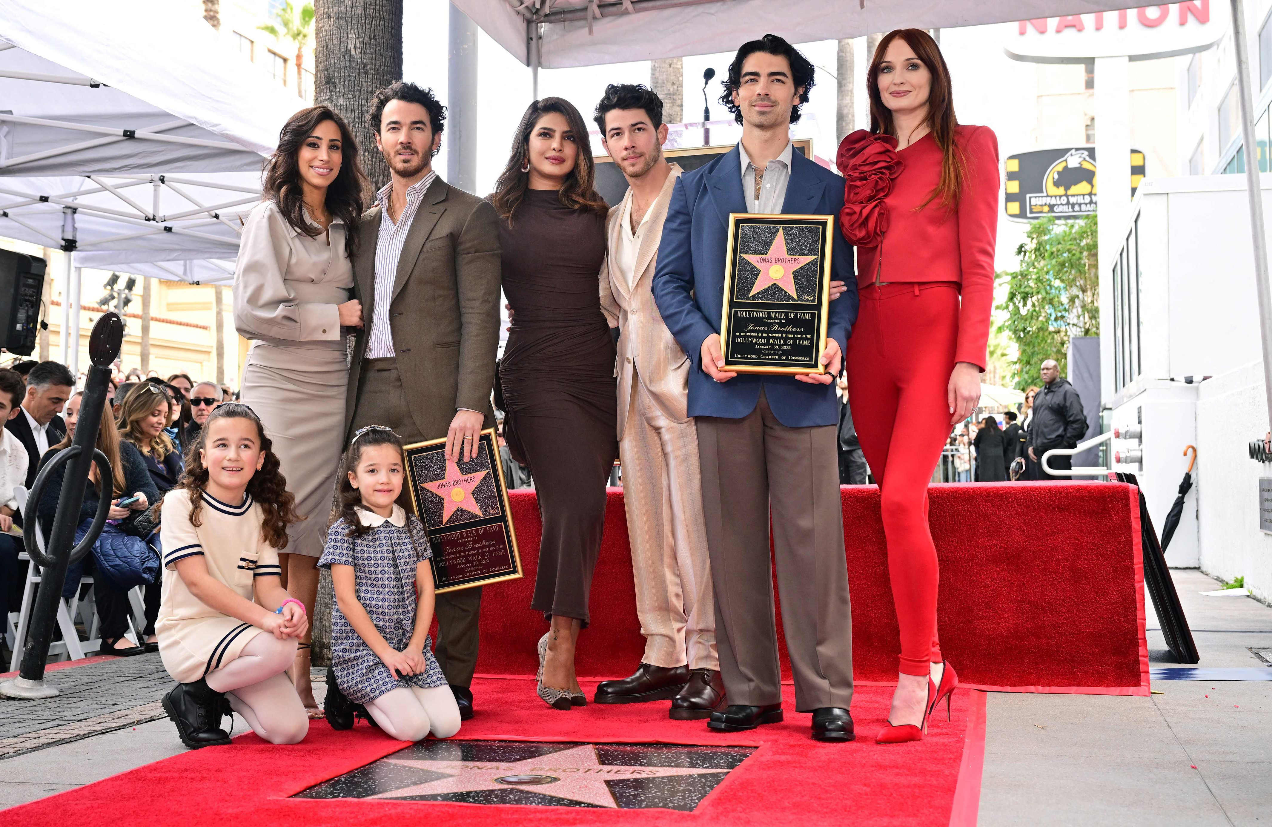 The Jonas Brothers, Kevin Jonas (second from left), Nick Jonas (center) and Joe Jonas (second from right), pose with their wives and children beside their Hollywood Walk of Fame Star after it was unveiled on Jan. 30, 2023 in Hollywood, Calif.