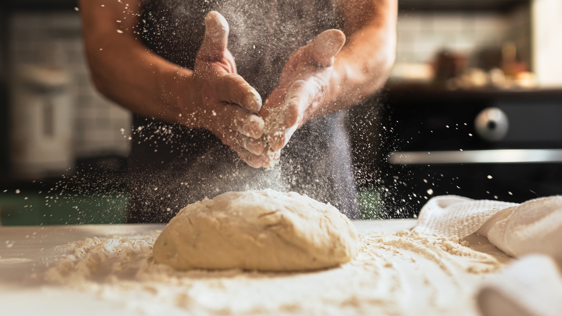 Chef’s hands spraying flour over the dough
