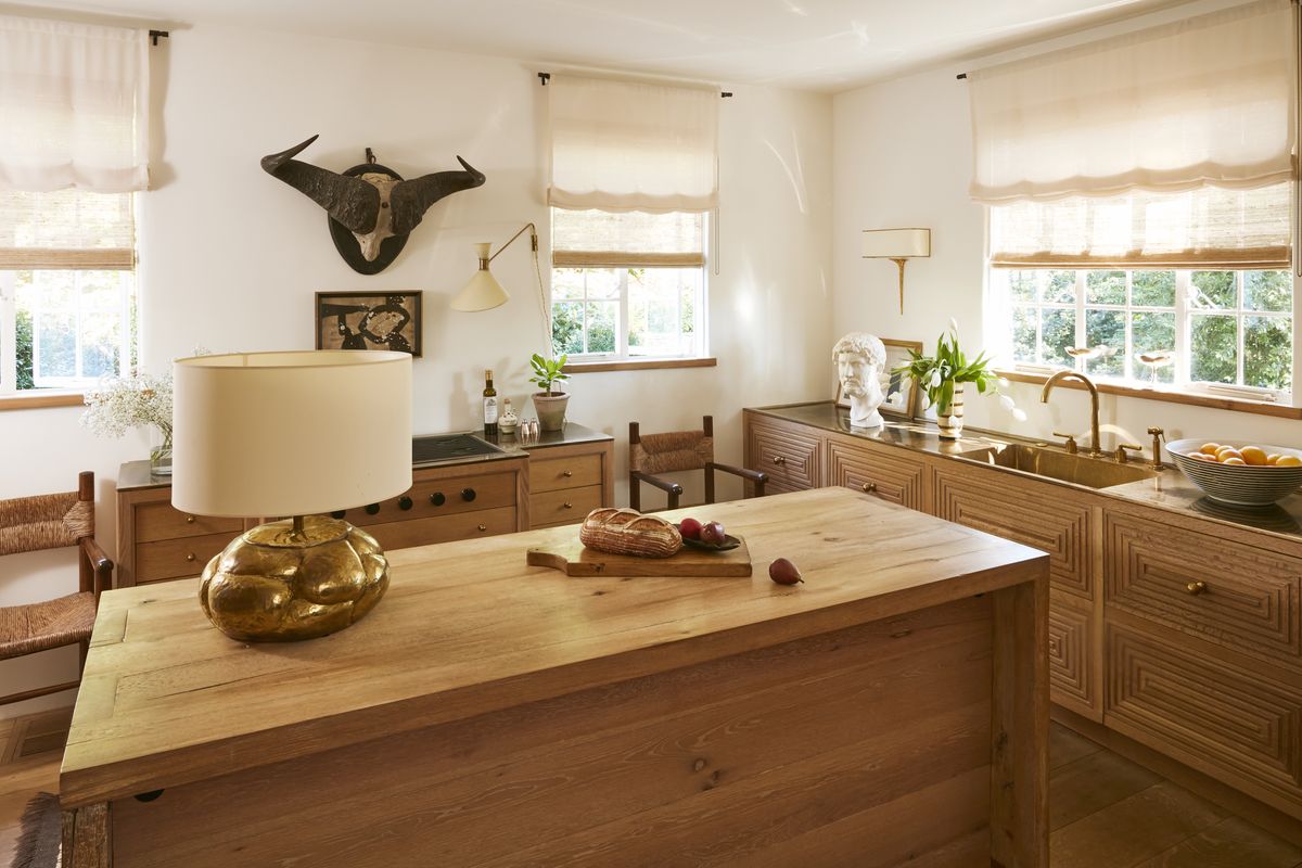 <p>Sunlight glints off bronze countertops in the kitchen, with low, white oak cabinetry inspired by David Adler’s Clow house in Chicago. </p>