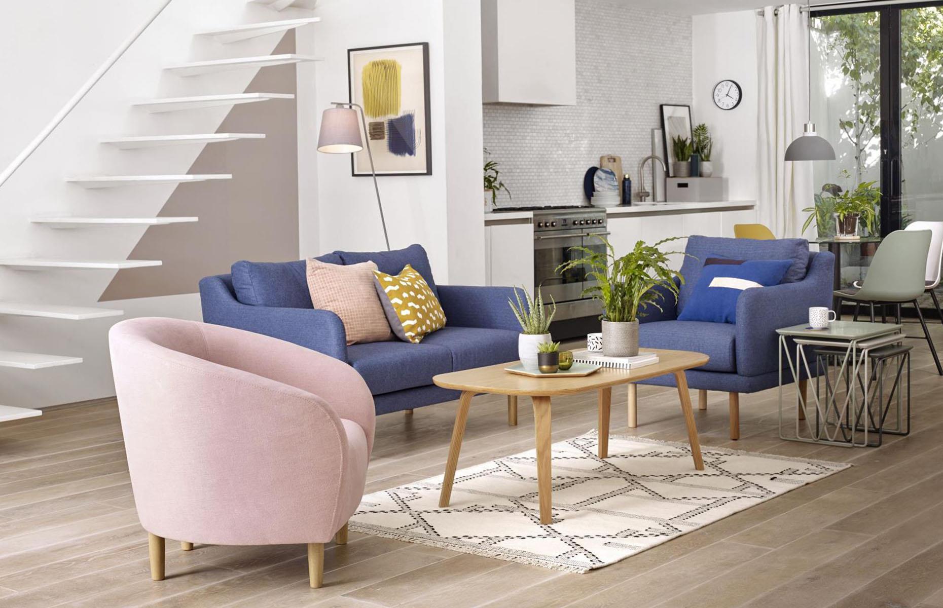 <p>If you want to create a distinction between your living zones without ending up with a jarring, disconnected scheme, decorate each individual area with different hues. Here, deep blue and powder pink armchairs define this sitting area, while pale sage accents dominate the kitchen. Pops of yellow create a cohesive link between the two spaces.</p>