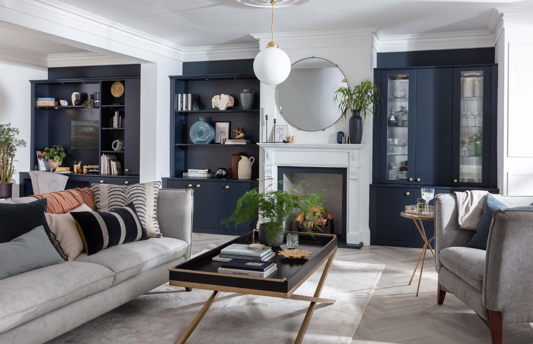 <p>Make use of older property alcoves by building matching bespoke storage that knits newly knocked-through rooms together. Painted dramatic navy blue, these built-in bookcases blend seamlessly with a workstation behind the living area to keep the whole space coherent. </p>