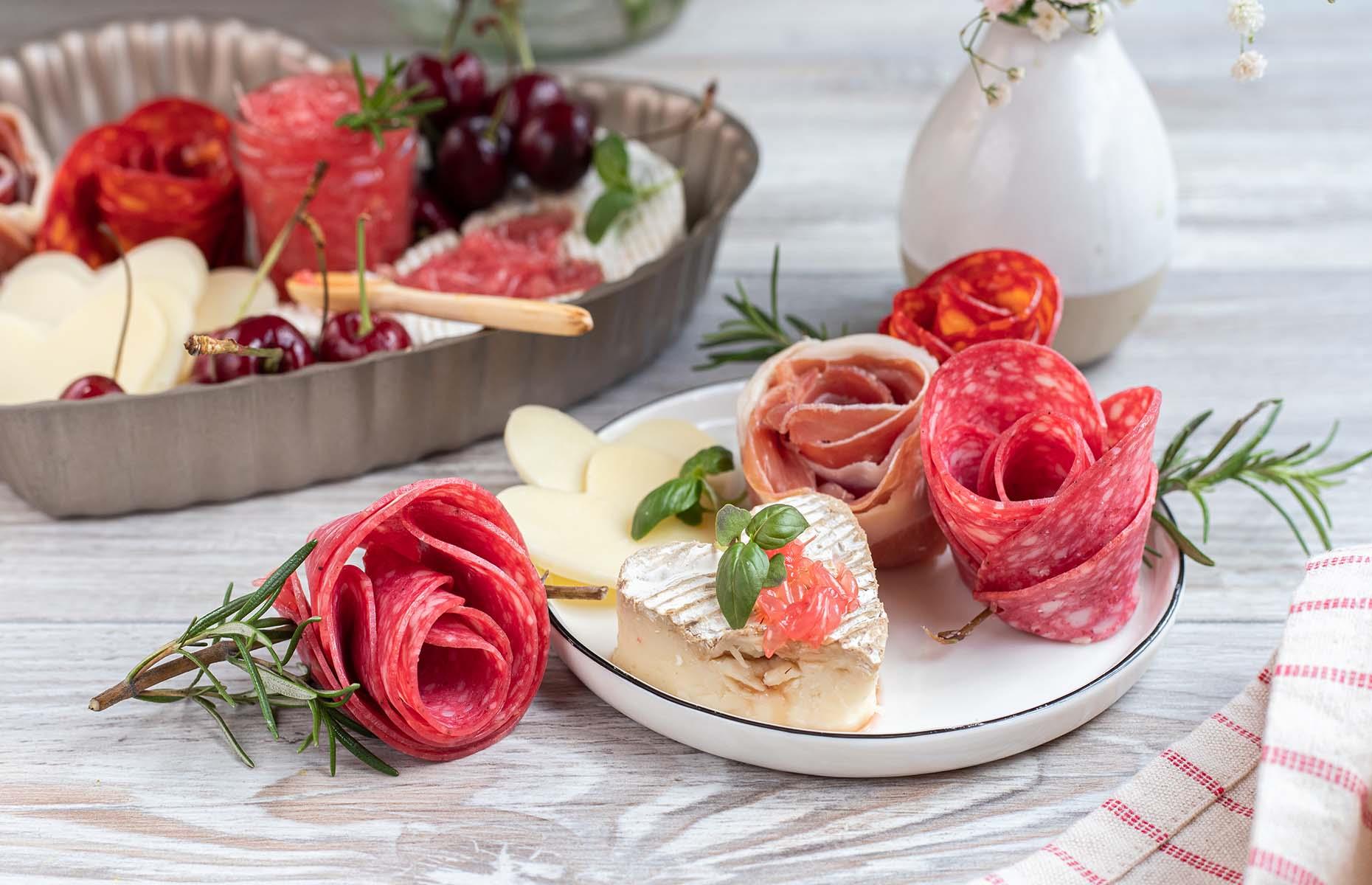 <p>One of the best things about grazing boards is that you can get really creative with the way you present your ingredients. Take these charcuterie roses, for example. To make them, all you need is a Champagne flute. Start by placing slices along the rim of the glass so that half of the round folds down in, and half out. Overlap the rounds around the flute, and layer them until you can no longer see the inside of the glass. Flip the flute over, and release your rose by twisting the glass back and forth gently.</p>
