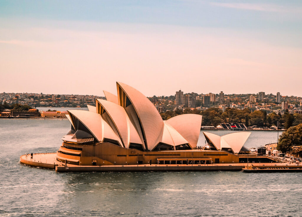 <p><em>By Catrina of 24 Hours Layover</em></p> <p>The Sydney Opera House – one of the greatest buildings of the 20th Century, is the most iconic <a href="https://24hourslayover.com/most-instagrammable-places-in-sydney/" rel="noreferrer noopener">photo spot in Sydney</a>. Not only that, it is one of the most famous and instantly recognised landmarks around the world and one of the world's most photographed buildings due to its unique shape!<br><br>Sitting in a prime location in Sydney Harbour, from every angle the Opera House looks different yet uniquely spectacular – whether you're on the stairs leading up to the Opera House, the Sydney Harbour Bridge, the Royal Botanic Gardens or Mrs Macquarie's Chair.<br><br>The World-Heritage listed Sydney Opera House is a significant landmark for Australians as it is the symbol of a modern Australia. It was designed by a Danish architect for a competition to design <a href="https://wanderwithalex.com/sydney-opera-house-and-others-around-the-world/">an Opera House for Sydney</a>. </p> <p>Two hundred and twenty three designs were submitted and this one was selected as the winning building! The building displays innovative engineering and architectural styles and was expected to take 4 years to build but ended up taking 14 years as many problems arose during the building process! </p> <p>The original estimate of the build was $7 million but it ended up costing over $100 million to build – talk about going over budget! Over a million roof tiles cover the Sydney Opera House, which was opened in 1973 by Queen Elizabeth II.<br><br>Often the Opera House is lit up at night in unique designs to commemorate special occasions such as Australia Day and Vivid Festival, which is really incredible to see!</p>
