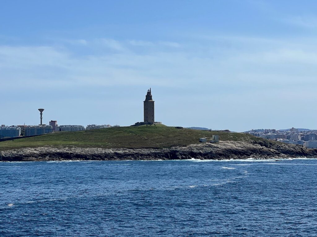 <p><em>By Melodie Rush of Travel Must Do's</em></p> <p>The Tower of Hercules is located in <a href="https://travelmustdos.com/la-coruna-spain-from-a-cruise-ship/" rel="noreferrer noopener">La Coruña, Spain</a> near the entrance of the harbor. It stands at a height of 185 feet. The building was first constructed by the Romans during the late 1st century A.D., although there may have been an earlier tower constructed in the same place. The tower was restored in the 18th century by architect Eustaquio Giannini and its Roman foundations were revealed during excavations in the 1990s.</p> <p>The Tower of Hercules has been a symbol of La Coruña and is an important piece of maritime history. It serves as a lighthouse for ships navigating the nearby waters today and its impressive light can be seen from up to 32 miles away! </p> <p>It has also been featured in a number of movies and television shows throughout the years, including Game of Thrones. One fun fact is that the local legend claims that the Tower was built by Hercules himself as an act of penitence after killing his own sons.</p> <p>It also serves as a reminder of the Roman Empire’s past influence in the region. This landmark has been designated a UNESCO World Heritage site in 2009 due to its cultural significance.</p> <p>The site also features a sculpture park, the Monte dos Bicos rock carvings from the Iron Age, and a Muslim cemetery.</p>