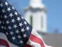 An American flag is seen near a church.