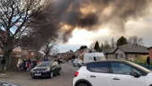 Smoke billows over houses as fire engines rush to the scene