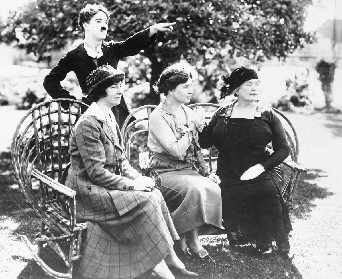<p>While filming the silent movie <i>Deliverance </i>in 1918, Helen Keller, along with her companion Polly Thomson and first teacher Anne Sullivan, met with famed movie comedian Charlie Chaplin.</p> <p>Here, all four are photographed together, looking off into the distance as Chaplin points something out to the ladies on the film set.</p>