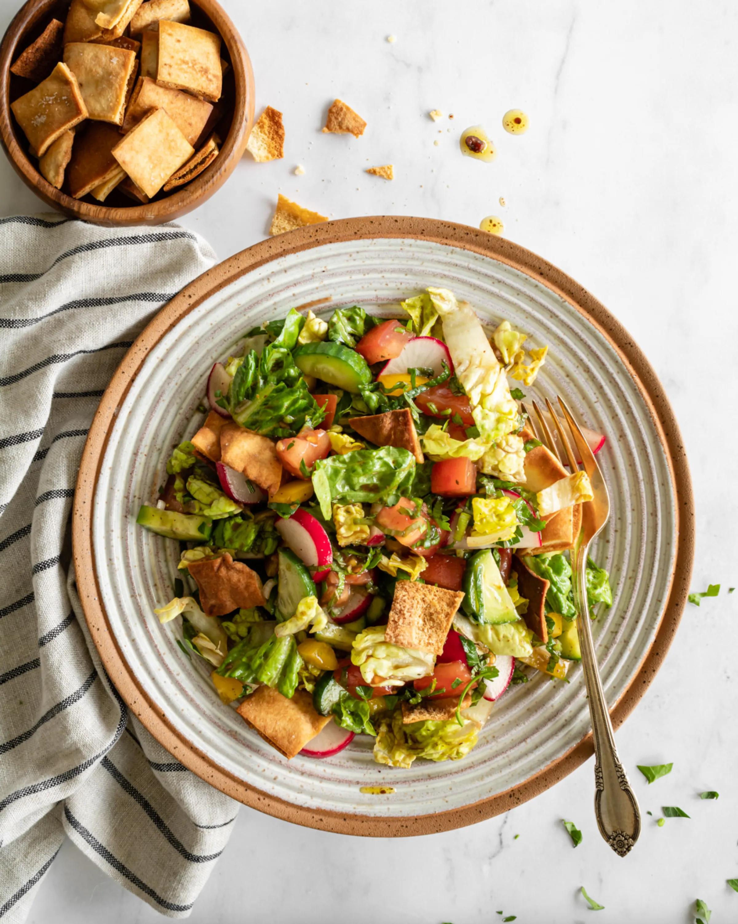 While this recipe for fattoush salad uses romaine, tomatoes, cucumbers, radishes, bell peppers, and herbs, you can really use whatever you have on hand. Open a bag of pita chips instead of baking your own for a lightning-fast lunch. (via <a href="https://www.brit.co/fattoush-salad/"><strong>Brit + Co.</strong></a>)