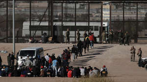 Migrants walk into U.S. custody after crossing the border from Mexico, Ciudad Juarez, Wednesday, March 29, 2023, a day after dozens of migrants died in a fire at a migrant detention center in Ciudad Juarez. ((AP Photo/Christian Chavez))