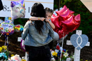 Shenae Beech holds her daughter Bowie, 4, as they pay their respects at a makeshift memorial by the entrance of the Covenant School Thursday, March 30, 2023, in Nashville, Tenn. Three children and three school staff members were killed by a former student in Monday’s mass shooting.