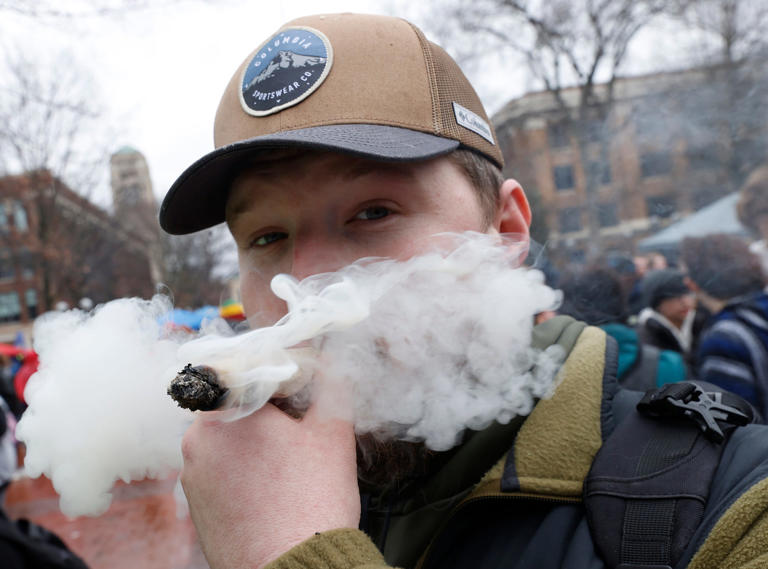 Standing at the Diag, Josh Hoskins, 32 of Waterford smokes his 12 inch joint with 16 grams of weed in it that he made using 12 rolling papers during Hash Bash 2023 on the campus of the University of Michigan in Ann Arbor on Saturday, April 1, 2023.