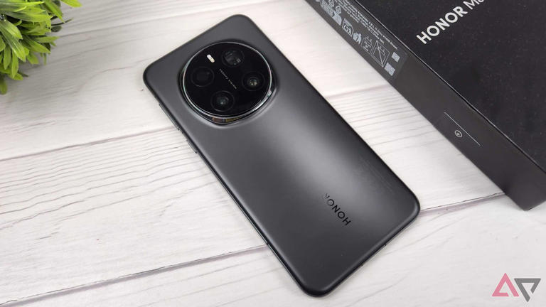 Honor Magic 7 Pro face down on a wooden table next to a plant and a black box