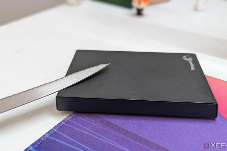 A black external hard drive with a metal blade on a desk