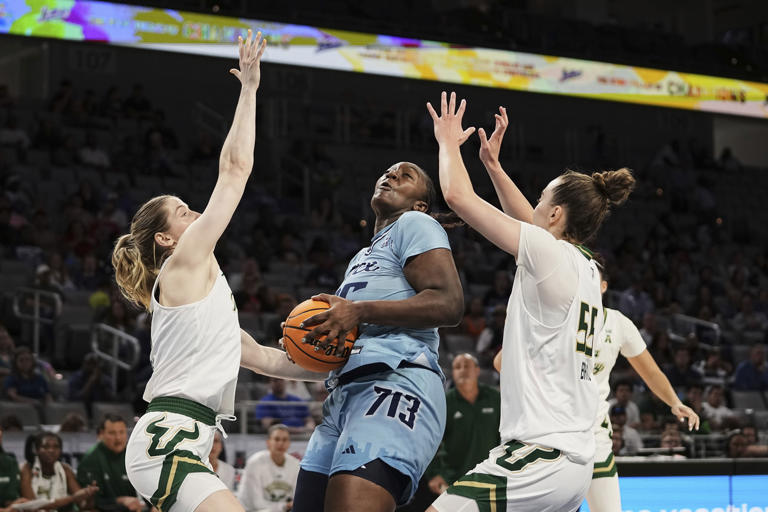 South Florida's Sammie Puisis, left, and Carla Brito (55) guard as Rice's Sussy Ngulefac, works to take a shot in the first half of an NCAA college basketball game during the womens final of the American Athletic Conference Tournament in Fort Worth, Texas, Wednesday, March 12, 2025. (AP Photo/Tony Gutierrez)