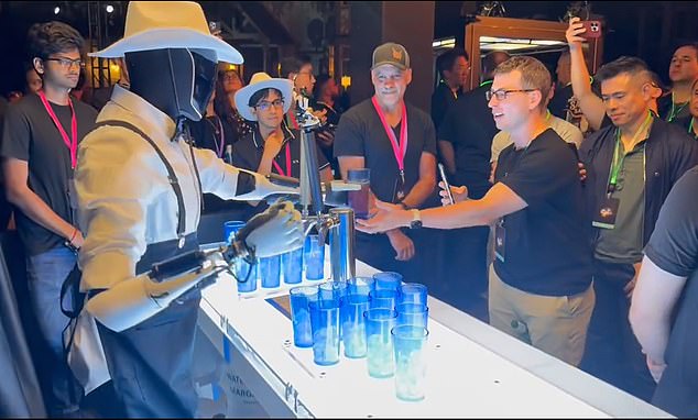 Tesla is building the Optimus robots - seen here serving drinks at an event in October. It later emerged the automatons were being remote controlled by humans