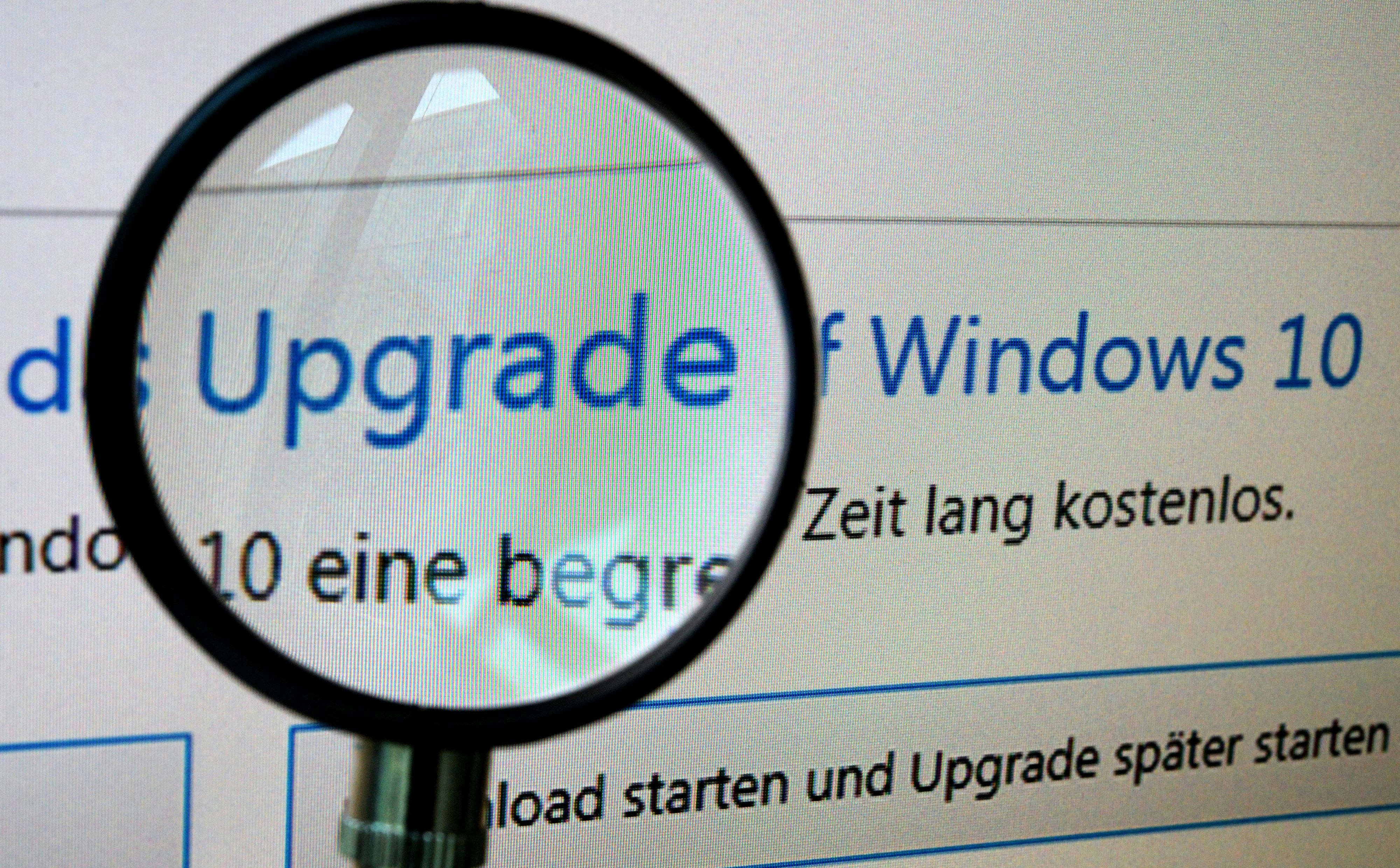 Ein Computerbildschirm zeigt das Update auf Windows 10 mit einer Lupe.