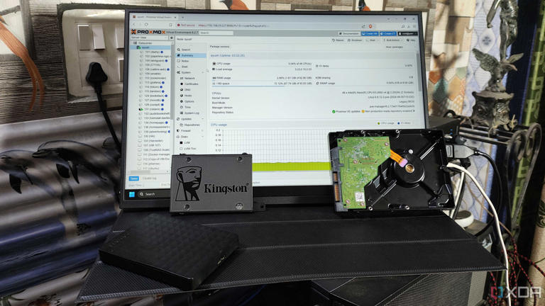 Some HDDs and a Kingston SSD placed in front of a monitor displaying the Proxmox web UI