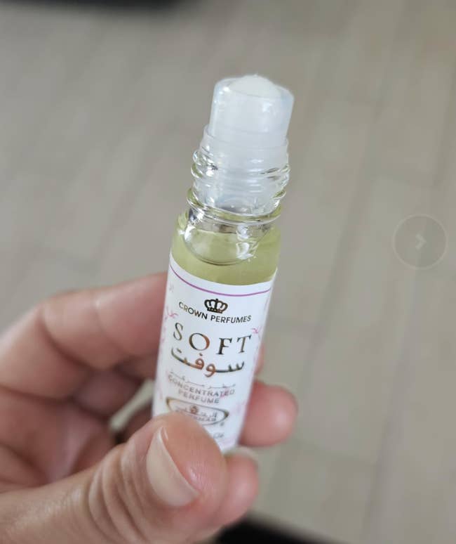 Person holding a small bottle of Crown Perfumes'
