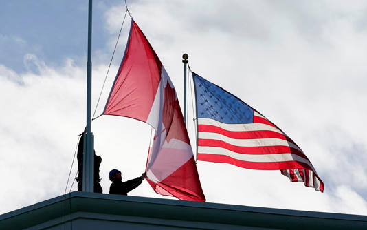 Washington State Park workers put up a new Canadian flag in front of an American flag