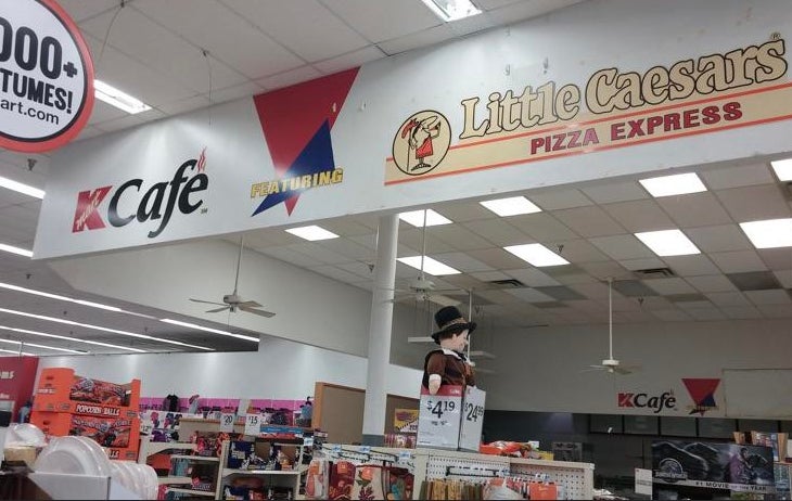 Interior of a Kmart store featuring a K Cafe and Little Caesars Pizza Express with costumes displayed on shelves