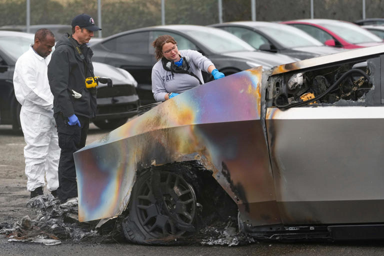Investigators from the Bureau of Alcohol, Tobacco, Firearms and Explosives and a member of the Seattle Fire Department examining burned Tesla Cybertrucks at a Tesla lot in Seattle in March. AP Photo/Lindsey Wasson