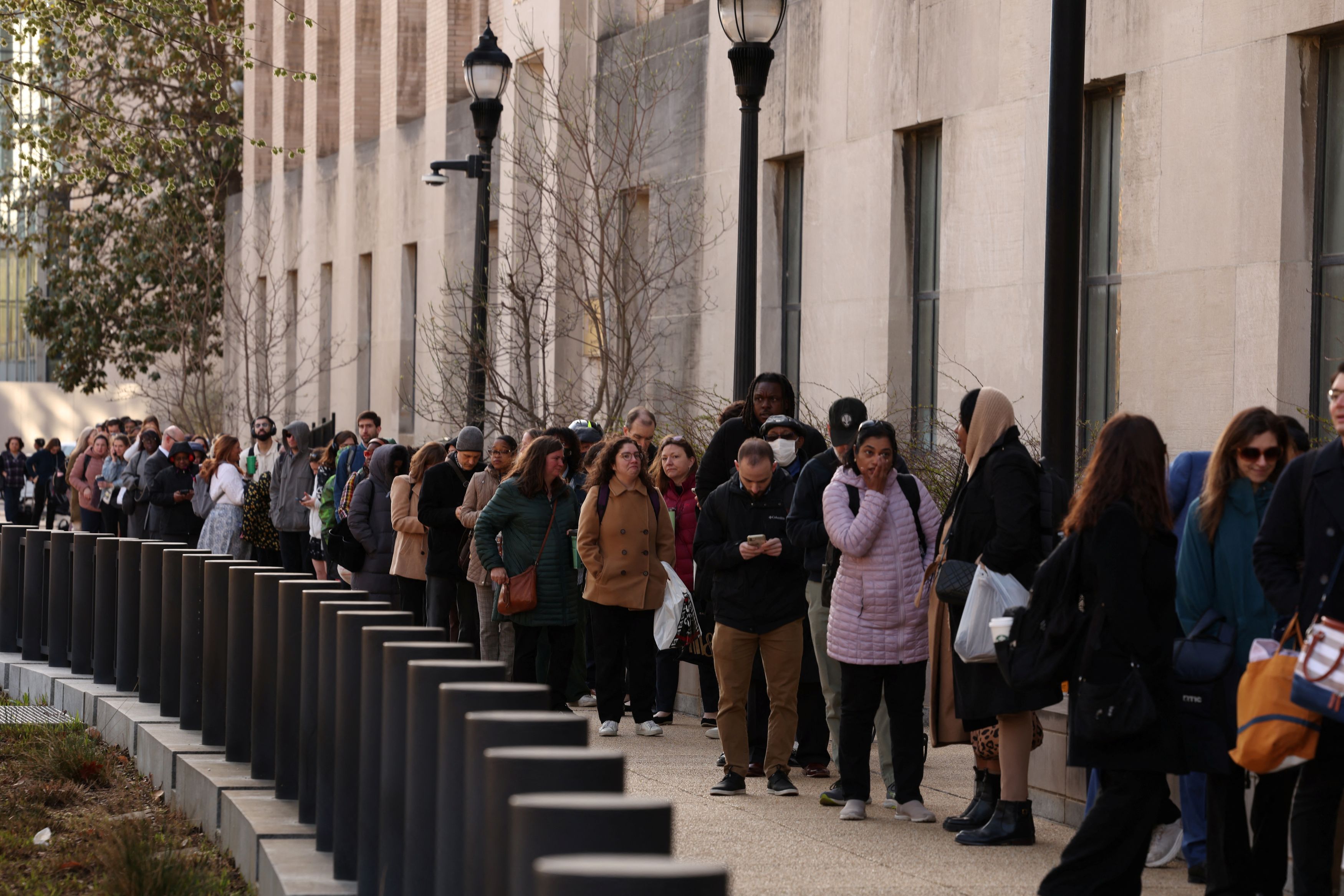 Employees of the Department of Health and Human Services queue outside the Mary E. Switzer Memorial Building in Washington on Tuesday, after the Trump administration began laying off staff.