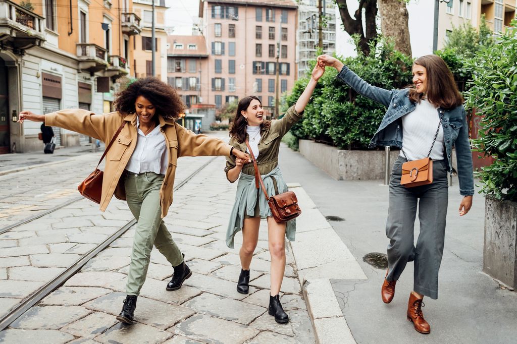 amigas de la mano caminando por la ciudad mientras hacen turismo