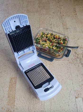 Vegetable chopper next to a container of diced fruit and vegetables, showcasing its function for food preparation