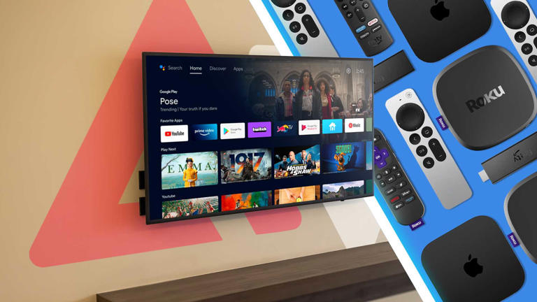 A smart TV mounted to a wall with a Google TV splash screen alongside various streaming boxes