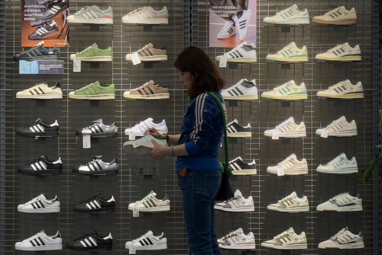 A woman tries out a shoe at an Adidas sportswear store inside a shopping mall, in Beijing, Saturday, April 12, 2025. ((AP Photo/Andy Wong))