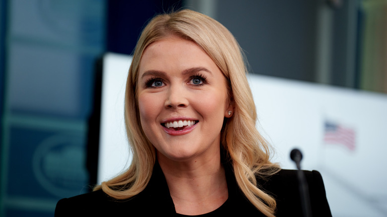 Karoline Leavitt smiles in a dark outfit
