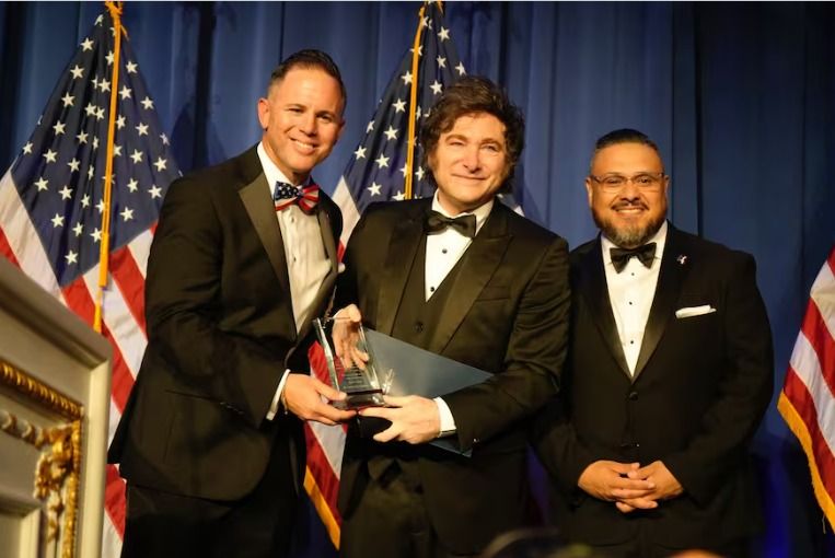 El dueño de una mudadora John Rourke, Javier Milei y el evangelista salvadoreño Glenn Parada, en ocasión de la entrega de un premio al mandatario argentino, el 3 de abril de 2025, en Mar-a-Lago.