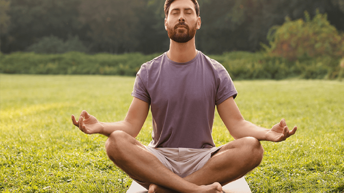 мужчина медитирует в позе лотоса на природе