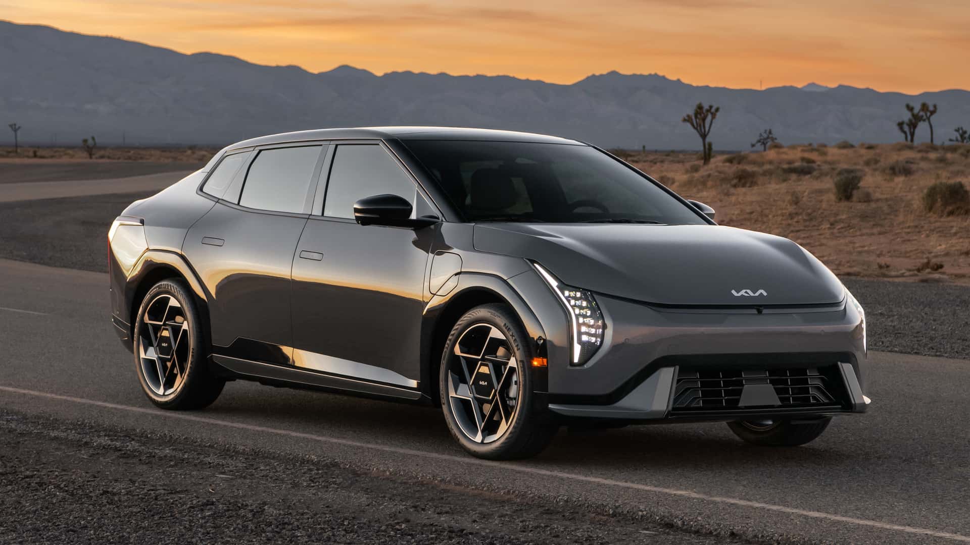 2026 Kia EV4 charging at a Tesla-compatible station, glowing under the city lights