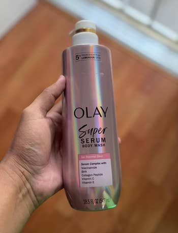 Person holding a bottle of Olay Super Serum Body Wash for normal skin with details of serum complex ingredients on the label