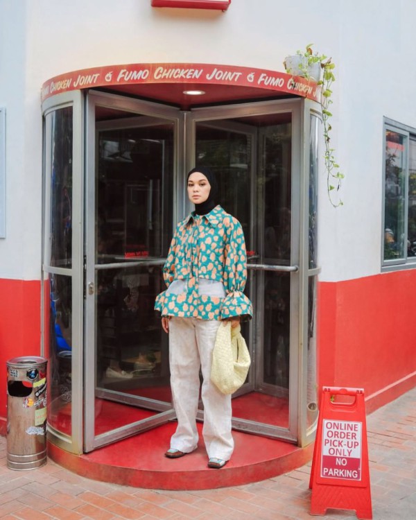 Blus dua warna oranye-hijau hutan, celana putih, jilbab hitam, sepatu sneaker berwarna putih, serta tas tote bag bernada krim Blus dua warna oranye-hijau hutan, celana putih, jilbab hitam, sepatu sneaker berwarna putih, serta tas tote bag bernada krim