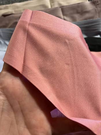 Person holding folded fabric; the texture is soft and shiny, suitable for clothing or home decor