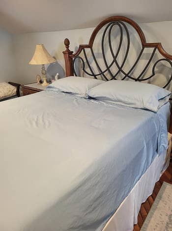 A neatly made bed with a decorative headboard and a bedside lamp