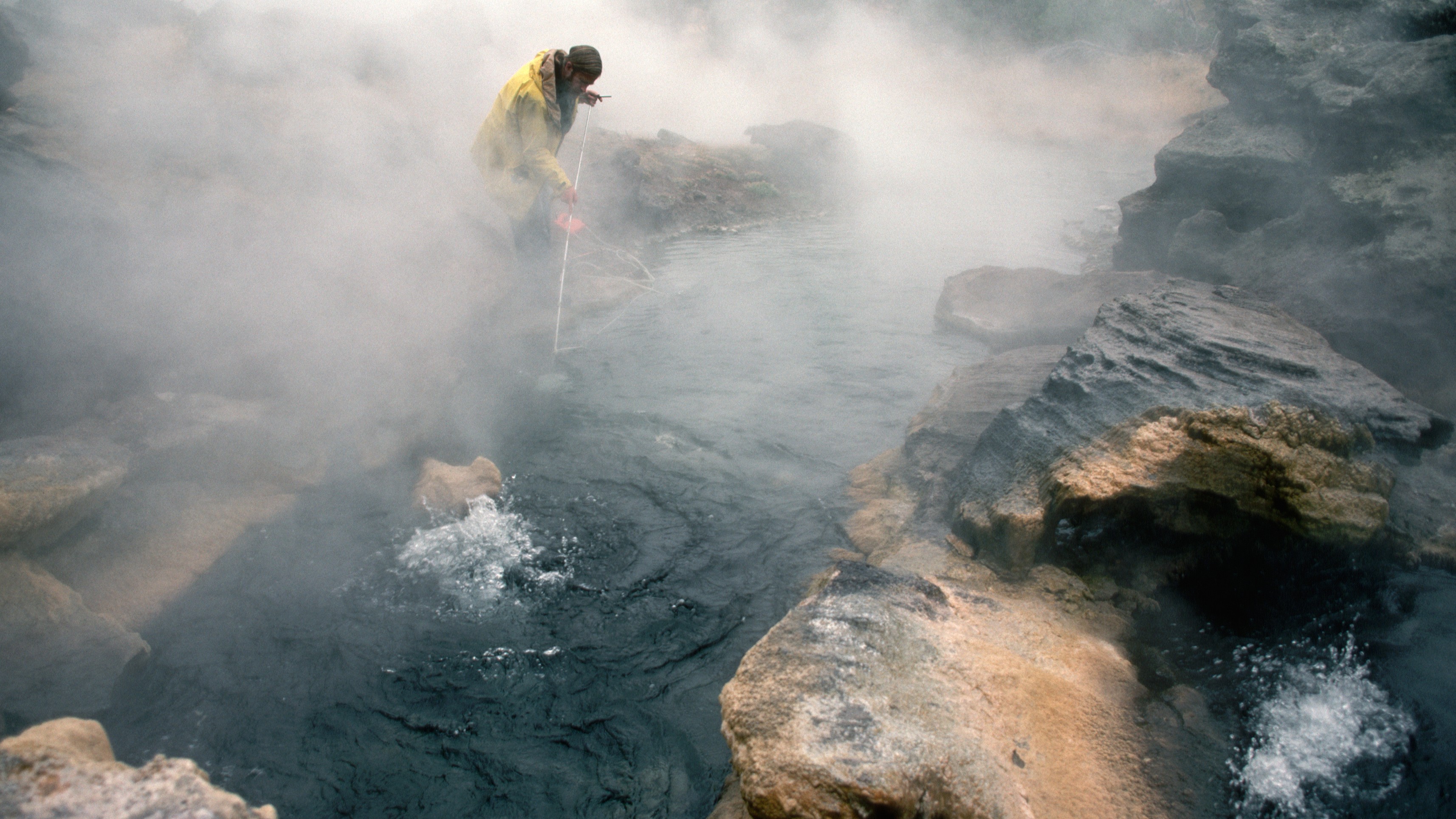 A scientist measuring helium concentration over a hot spring at Yellowstone.