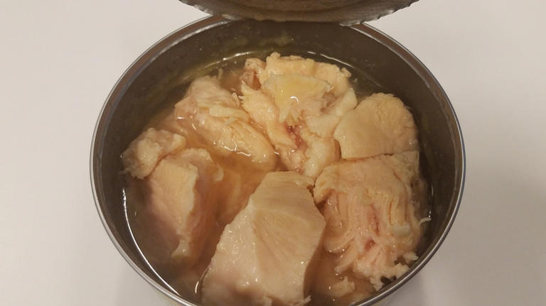 An opened can of canned chicken in broth